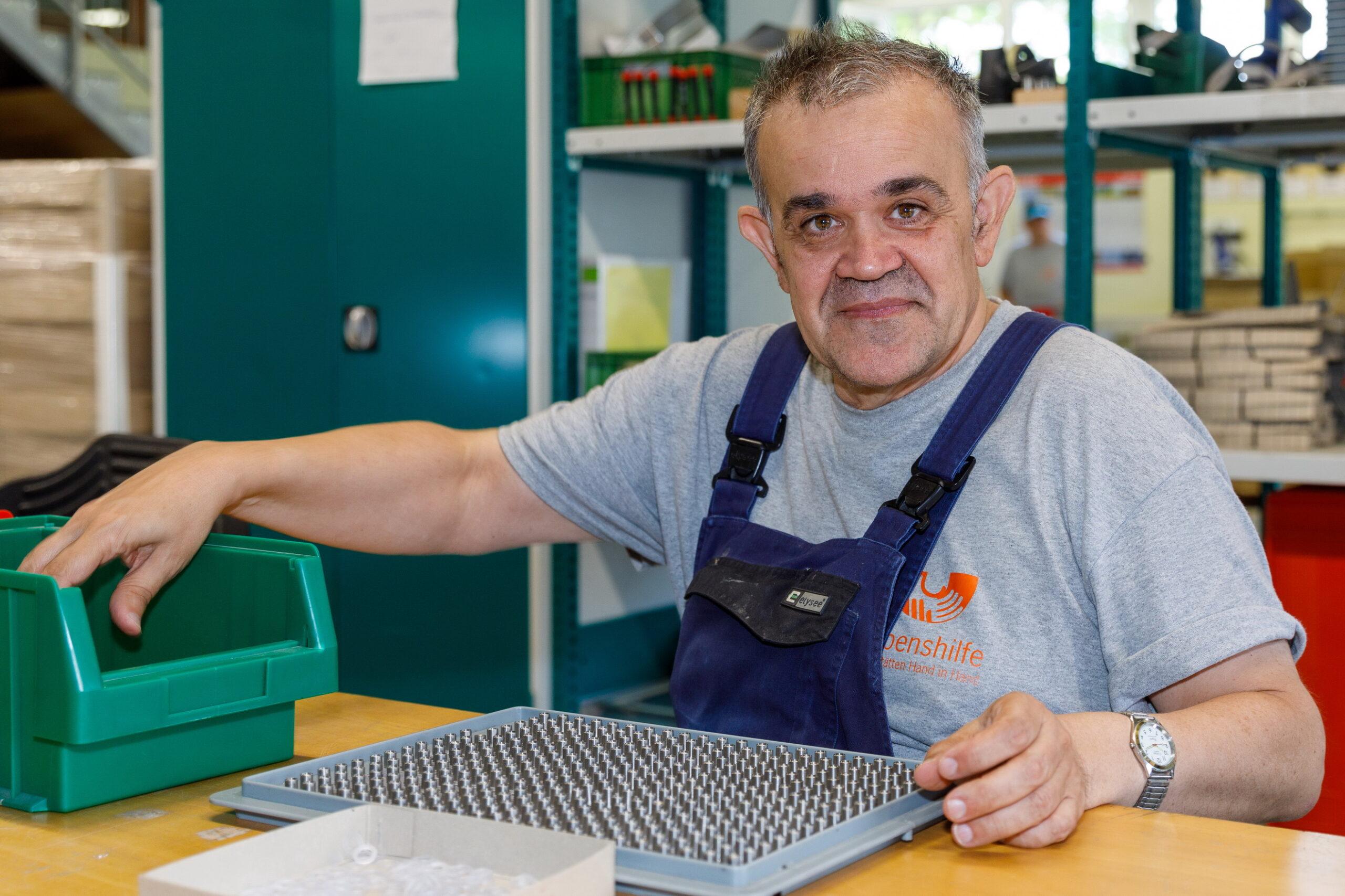 Auf dem Bild zu sehen: Ein Mitarbeiter bei der Konfektionierung von Edelstahlabstandshaltern.